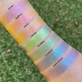 Top angled arm swatches on fair skin in tone of Auric Deep Iridescent Multichrome Eyeshadow shifts compared to Cerise, Saffron, Citron Viridian, Cerulean and Lapis Lazuli.