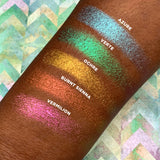 Top angled arm swatches on deep skin tone of Azure Deep Iridescent Multichrome Eyeshadow shifts compared to Verte, Ochre, Burnt Sienna, Vermilion