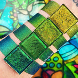 Top angled Weathered Jewelled Multichrome Eyeshadow overtop arm swatches on fair skin tone compared to Patina, Gargoyle, Trefoil
