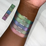 Top angled arm swatches on deep skin tone of Royal Plum Earth Vibrant Multichrome Eyeshadow shifts compared to Hedge Maze, Wall of Ivy, Climbing Vine and Statue Garden