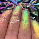 Low angled finger swatches on fair skin tone of Gloaming Glitter-Type Iridescent Multichrome Eyeshadow shifts compared to Aura, Glint, Lux