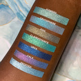 Top angled arm swatches on deep skin tone of Calx compared to Icerberg, Cryosphere, Fog, Clairvoyance, Ursa and Frosted