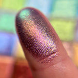 Close up finger swatch on fair skin tone of Royal Plum Earth Vibrant Multichrome Eyeshadow
