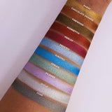 Top angled are swatches on fair skin tone of The Ultra Metals Collection including Chocolate Orange Foiled Eyeshadow next to Karat, Firewood, Poinsettia, Merlot, Frosted, Subzero, Spruce, Filigree, Icicle, Char