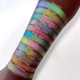 Top angled arm swatches on deep skin tone of Climbing Vine Earth Vibrant Multichrome Eyeshadow shifts compared to Wall of Ivy, Iron gate, Royal Plum, Statue Garden, Hedge Maze, Royal Pear, Estate, Bronze Fountain, Royal Peach and Cobblestone