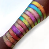 Top angled arm swatches on deep skin tone of Hilt Electric Multichrome Eyeshadow shifts compared to Mural, Motif, Tessera, Niello, Quest, Rayonnant, Flashed Glass, Cinder, Oriel and Signet
