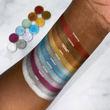 Top angled arm swatches on deep skin tone of Chocolate Orange Ultra Metals Foiled Eyeshadow compared to Poinsettia, Firewood, Karat, Spruce, Subzero, Frosted, Filigree, Merlot, Char, Icicle