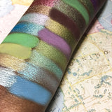 Close up right angled arm swatches on deep skin tone of 66.5 N Collection including Caribou Shimmer Eyeshadow
