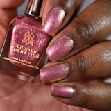 Close-up shot of Cosmopolitan nail lacquer applied to finger nails on a darker skin tone, with nail lacquer bottle in hand