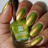 Close-up shot of Spicy Margarita nail lacquer applied to finger nails on a darker skin tone, with nail lacquer bottle in hand