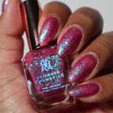 Close-up shot of Strawberry Mojito nail lacquer applied to finger nails on a darker skin tone, with nail lacquer bottle in hand