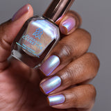 Close up shot of nails done with Radiance nail lacquer on deep skin tone holding the nail lacquer bottle
