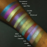 Top angled arm swatches on deep skin tone Witchcraft vs. Alchemy Collection including Aqua Fortis Duochrome Eyeshadow next to Necromancer, Panacea, Aqua Vitae, Crucible, Sol, Wormwood, Elixir, Cinnabar, Calx, Arcana, Rune
