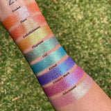 Top angled arm swatches on fair skin tone of Trinket Glitter Multichrome Eyeshadow shifts compared to Flare, Embellishment, Flagstone, Ciel, Etched, Glaziers Mark and Adornment