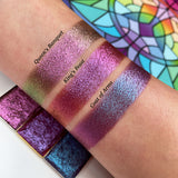 Top angled arm swatch on fair skin of Coat of Arms Hybrid Multichrome Eyeshadow shifts compared to Queen's Banquet and King's Feast