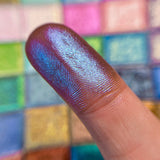Close up finger swatch on fair skin tone of Cerulean Deep Iridescent Multichrome Eyeshadow