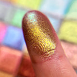 Close up finger swatch on fair skin tone of Estate Earth Vibrant Multichrome Eyeshadow