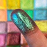 Close up finger swatch on fair skin tone of Flagstone Glitter Multichrome Eyeshadow