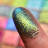 Close up finger swatch on fair skin tone of Hedge Maze Earth Vibrant Multichrome Eyeshadow