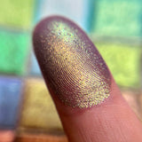 Close up finger swatch on fair skin tone of Iron Gate Earth Vibrant Multichrome Eyeshadow