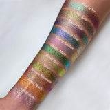 Top angled arm swatches on medium skin tone of Royal Plum Earth Vibrant Multichrome Eyeshadow shifts compared to Wall of Ivy, Iron Gate, Climbing Vine, Statue Garden, Hedge Maze, Royal Pear, Estate Bronze Fountain, Royal Peach and Cobblestone