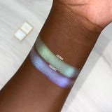 Top angled arm swatches on deep skin tone of Radiance Series 2 Iridescent Multichrome Eyeshadow shifts compared to Lucidum