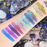 Top angled arm swatches on fair skin tone Witchcraft vs. Alchemy Collection including Aqua Fortis Duochrome Eyeshadow next to Rune, Elixir, Sol, Wormwood, Necromancer, Aqua Vitae, Arcana, Cinnabar, Crucible, Panacea, Calx