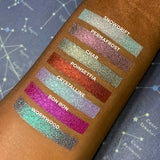 Top angled arm swatches on deep skin tone of Wormwood compared to Snowdrift, Permafrost, Char, Poinsettia, Crystalline and Bon Bon