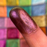 Close up finger swatch on fair skin tone of Queen's Banquet Hybrid Multichrome Eyeshadow