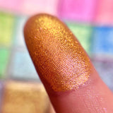 Close up finger swatch on fair skin tone of Royal Peach Earth Vibrant Multichrome Eyeshadow