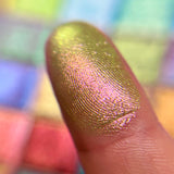 Close up finger swatch on fair skin tone of Royal Pear Earth Vibrant Multichrome Eyeshadow