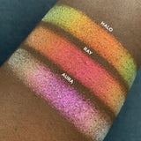 Top angled arm swatches on deep skin tone of Ray Iridescent Multichrome Eyeshadow shifts compared to Halo, Aura