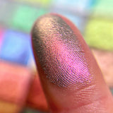 Close up finger swatch on fair skin tone of Statue Garden Earth Vibrant Multichrome Eyeshadow