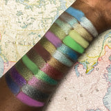 Top angled arm swatches on deep skin tone of 66.5 N Collection including Permafrost Duochrome Eyeshadow